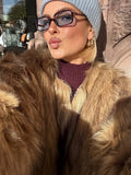 Woman wearing a faux fur jacket, light blue beanie, and sunglasses