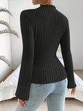 Back view of a woman in a black ribbed knit long-sleeve top with flared sleeves and a mock neckline, paired with blue jeans.