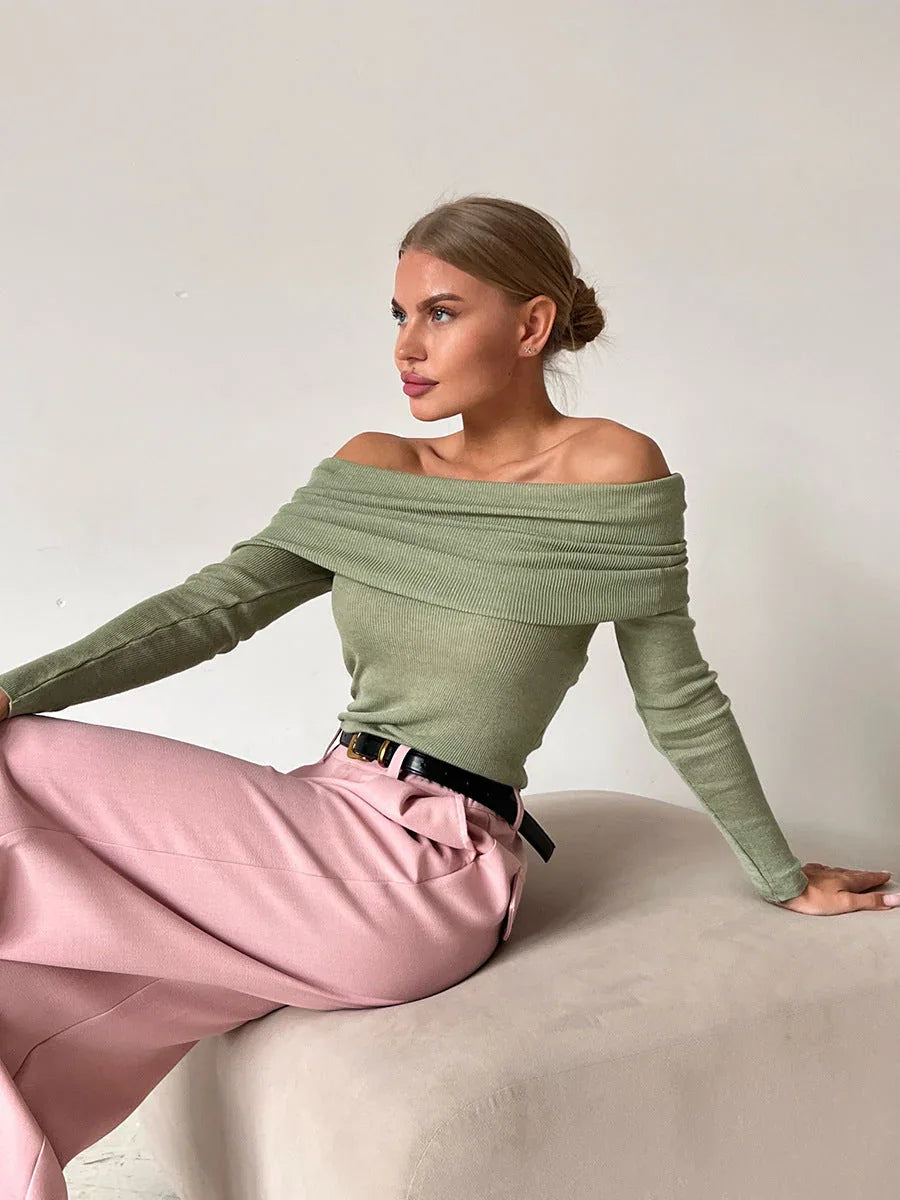 Woman wearing a green off-the-shoulder ribbed knit sweater with long sleeves.