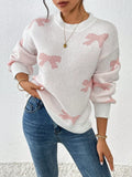 Woman in a white knit sweater with a pink bow print, showing off the relaxed fit.