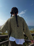 Woman posing in a relaxed fit chevron knit cardigan by the ocean