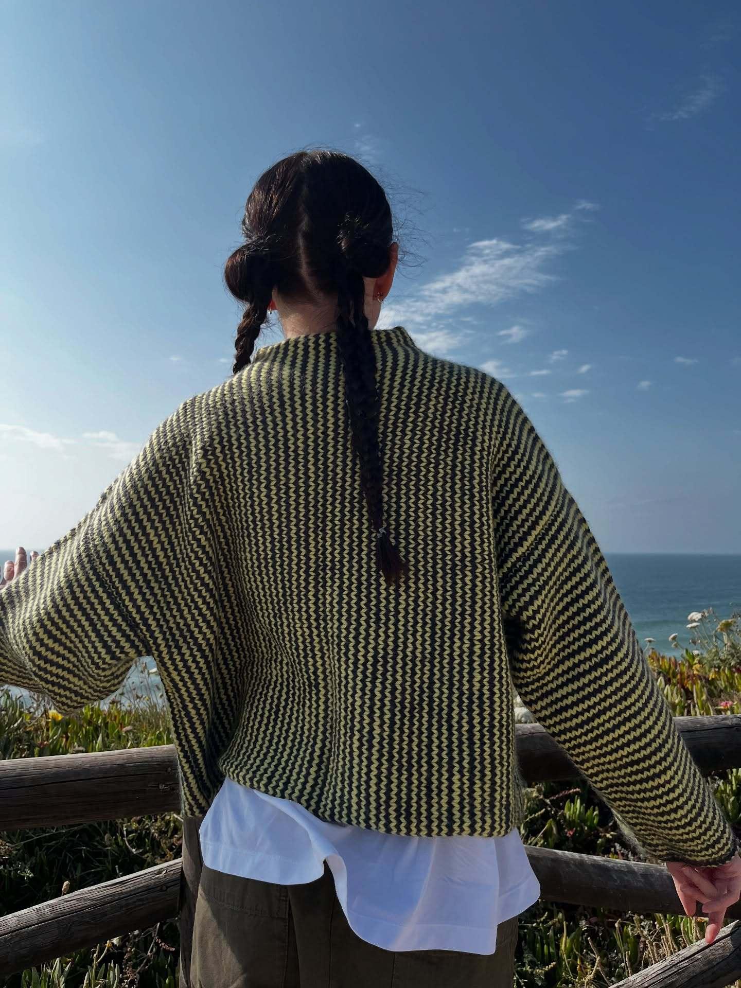 Woman posing in a relaxed fit chevron knit cardigan by the ocean