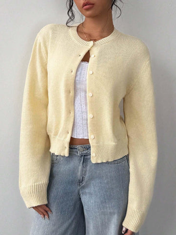 Woman wearing a light yellow button-front knit cardigan with long sleeves.