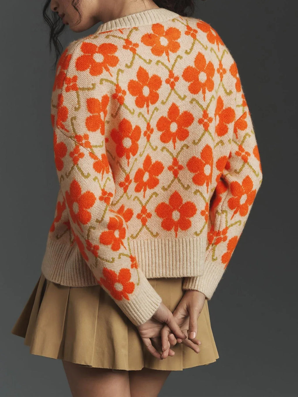 Back view of a woman wearing a beige cardigan with an orange floral print.