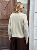 Back view of a woman wearing a cream argyle knit cardigan.