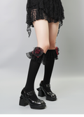 View of the side of black knee-high socks with floral lace trim.