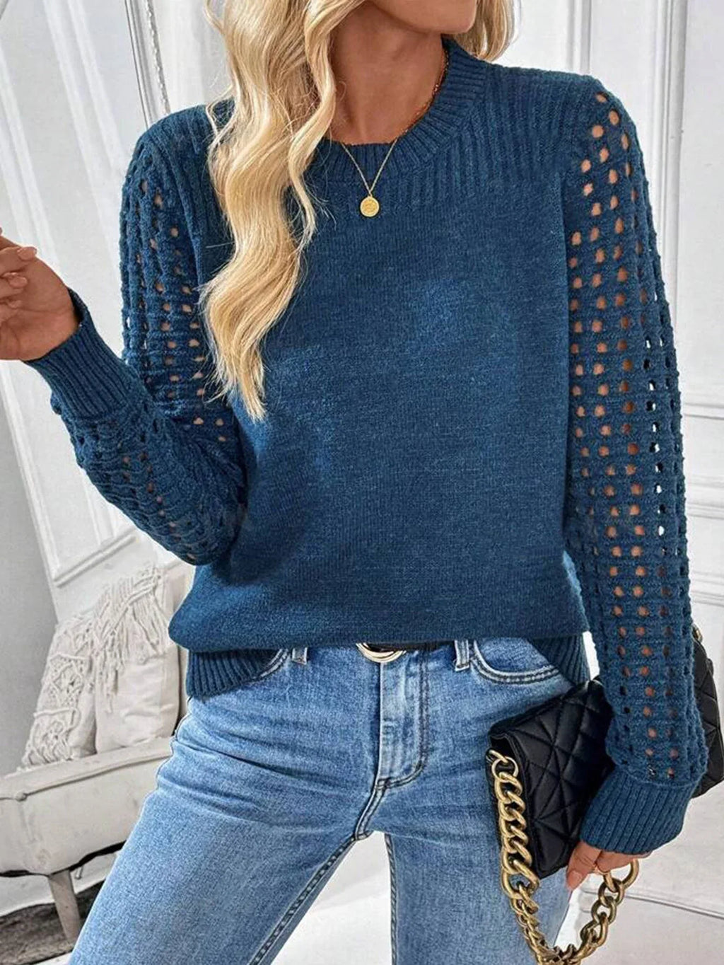 Woman in a blue knit sweater with openwork sleeves and blue jeans