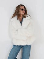 Woman wearing a white faux fur jacket with a lapel collar and medium wash denim jeans, posing against a white background.
