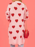 Back view of a woman wearing a pink knit cardigan with a repeating red heart motif.
