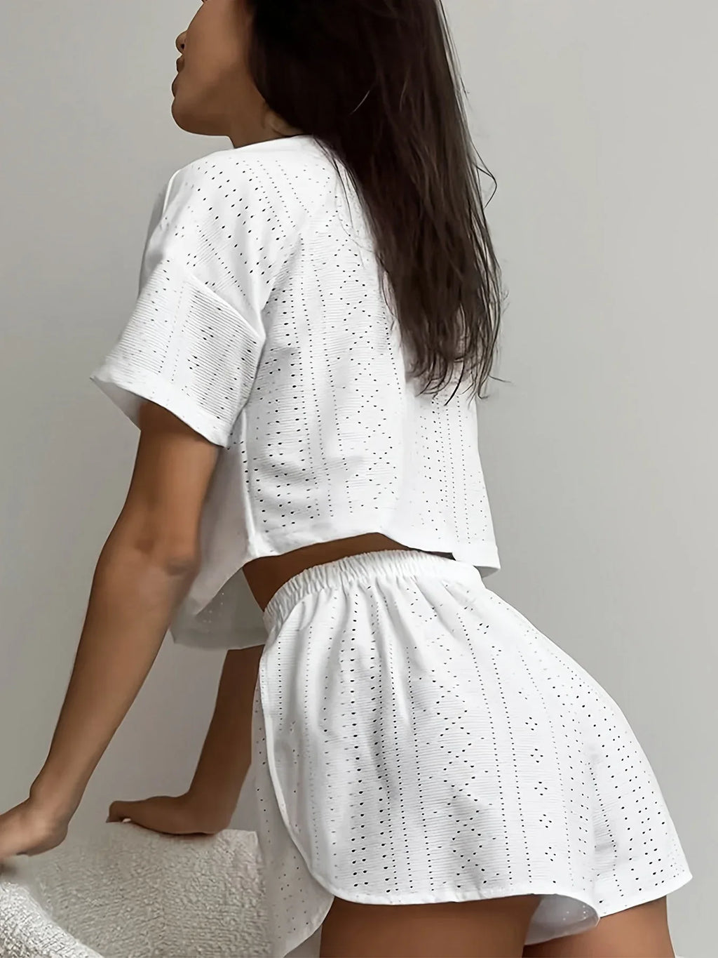 Side view of a woman in a white cropped eyelet t-shirt and matching white eyelet shorts