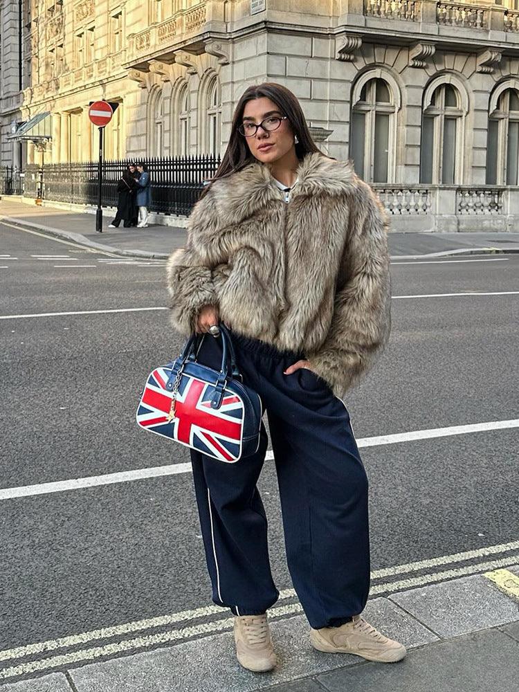 Woman wearing a brown faux fur jacket with a collared neckline and zipper closure, paired with navy track pants and sneakers. Main image