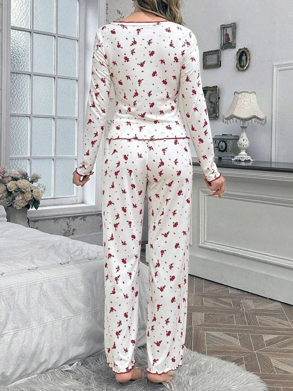 Back view of woman in white pajamas with red floral print and scalloped trim.
