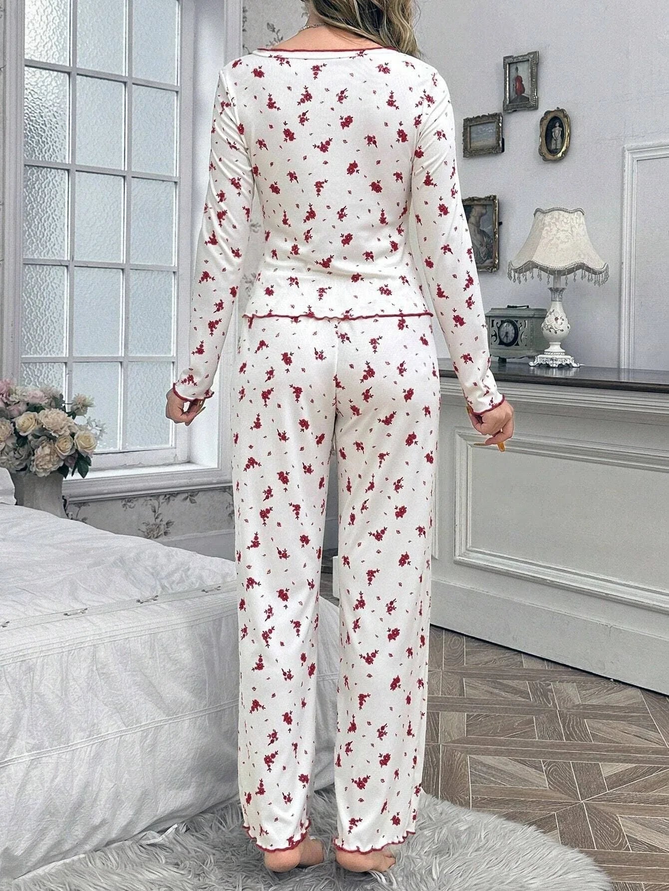 Back view of woman in white pajamas with red floral print and scalloped trim.