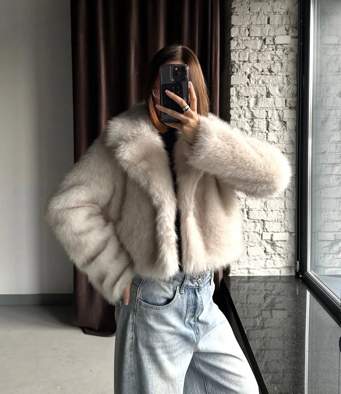 Woman wearing a cream-colored faux fur cropped jacket with a notch lapel collar and long sleeves.