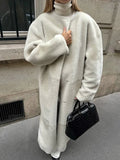 Woman in a cream sherpa coat, showcasing the textured fabric and stand collar.