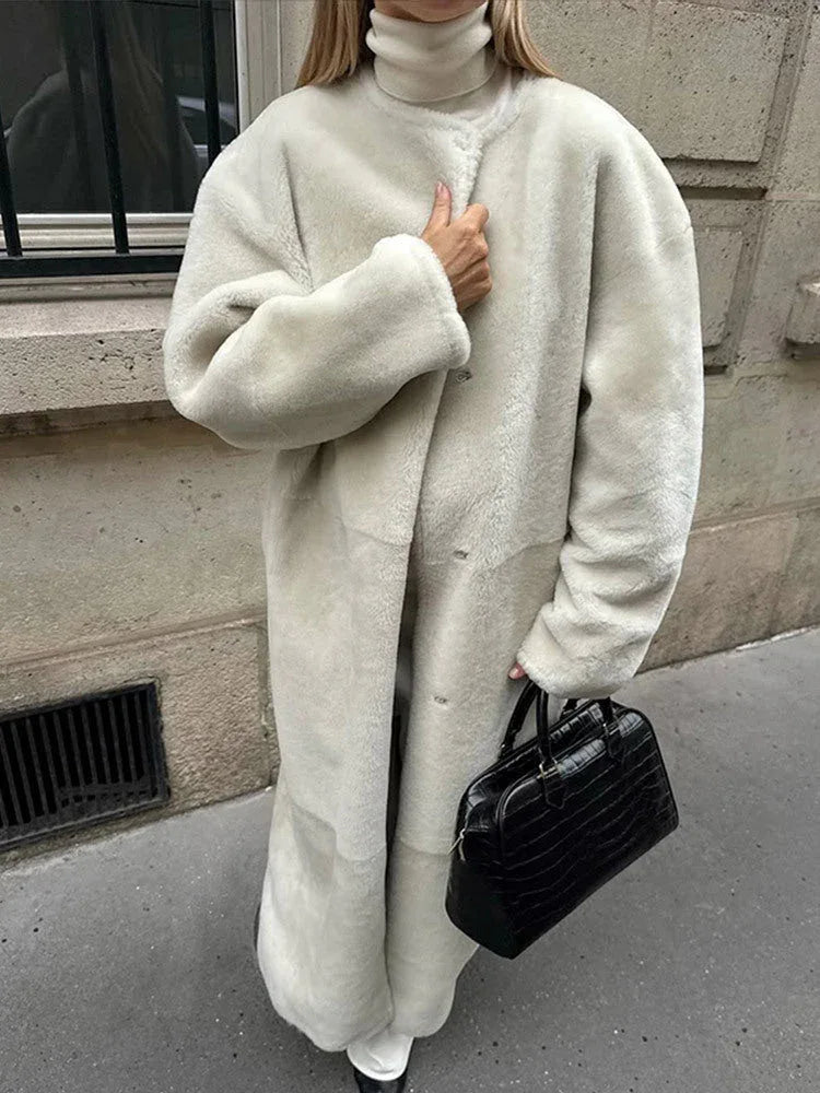 Woman in a cream sherpa coat, showcasing the textured fabric and stand collar.