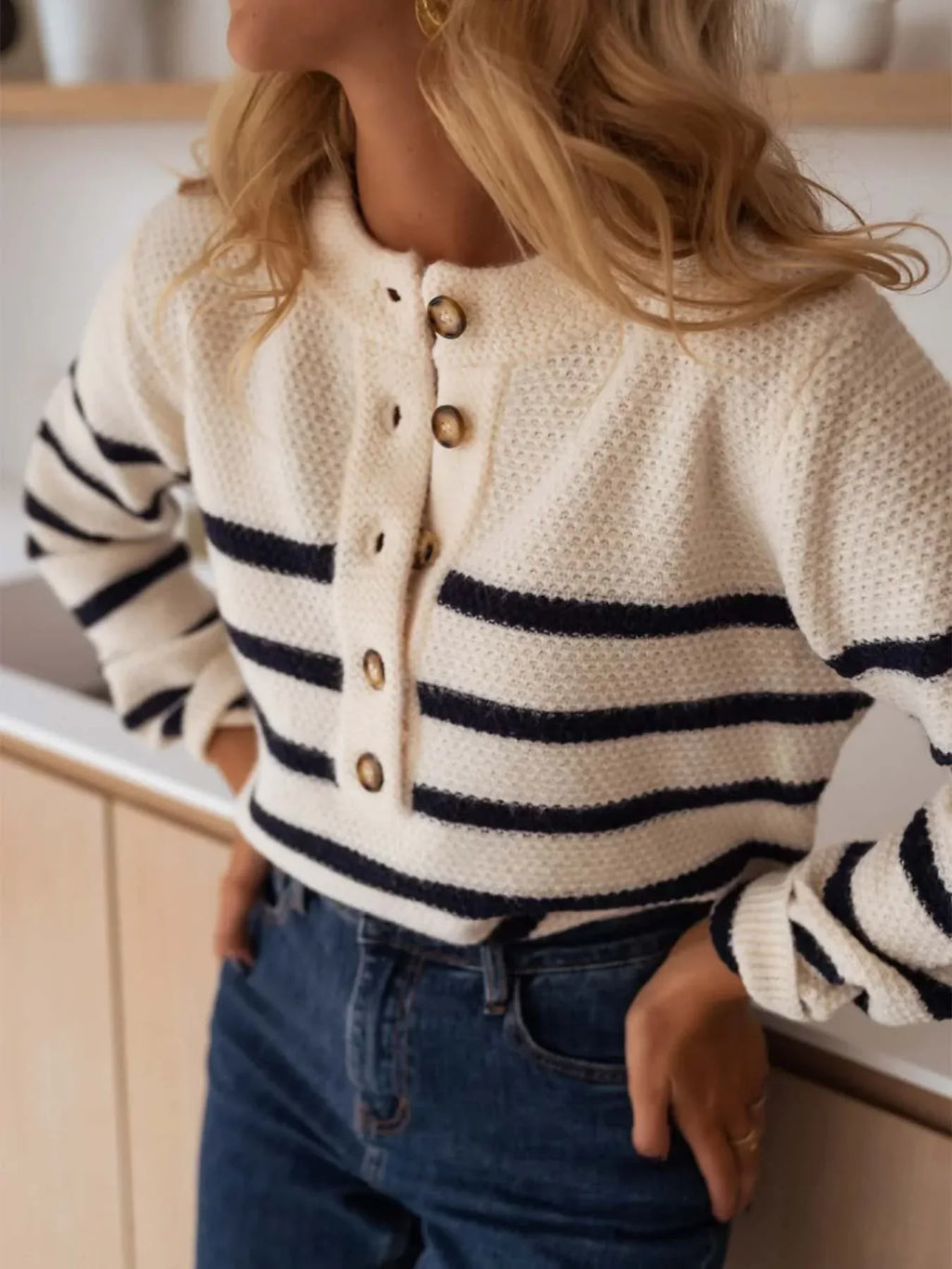 Woman with hands on hips wearing a striped knit sweater.