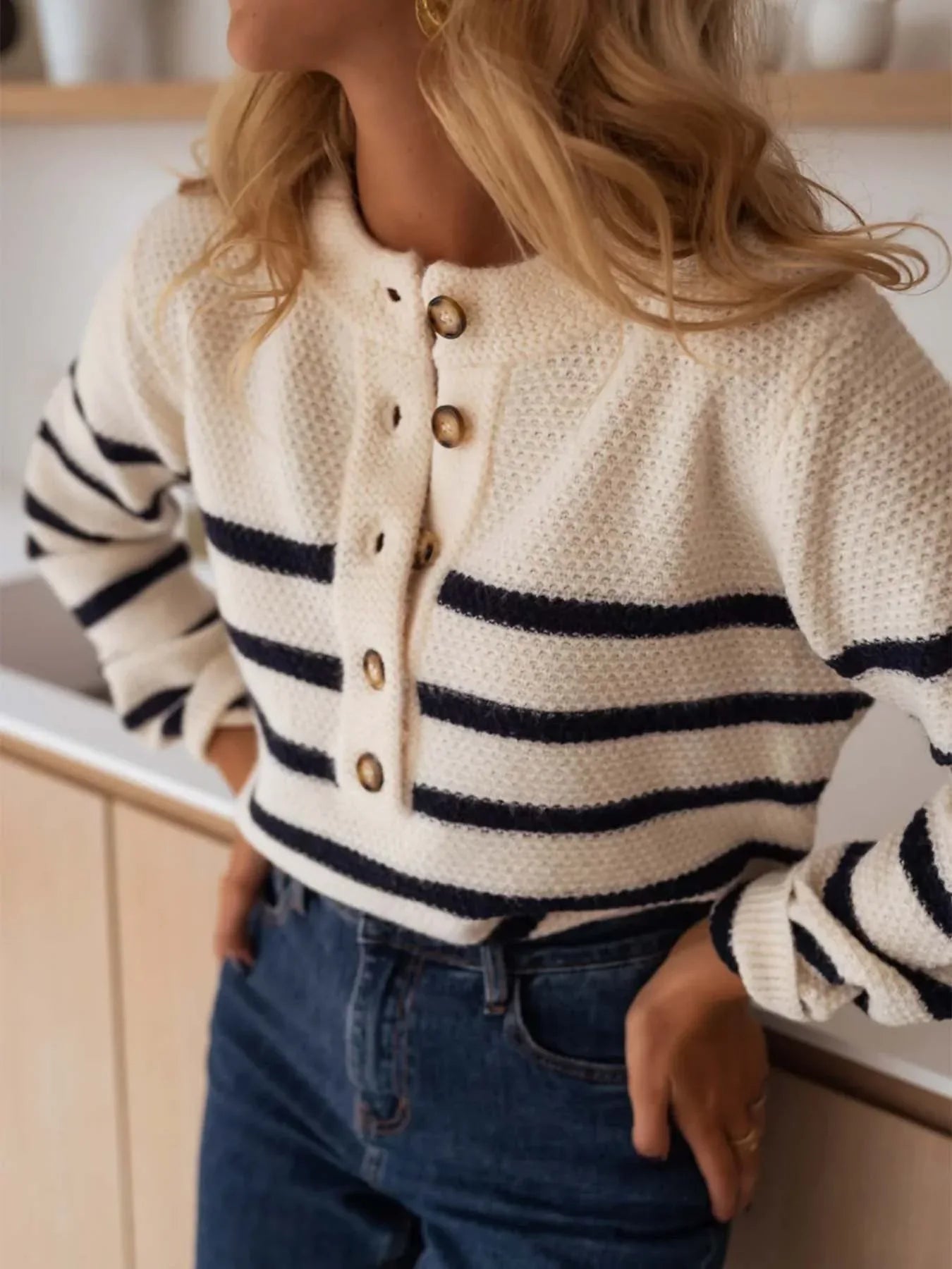 Woman with hands on hips wearing a striped knit sweater.
