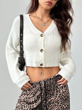 Woman in a white cropped cardigan layered over a white tank top, paired with leopard print pants