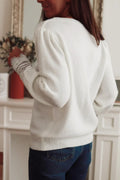 Back view of a woman wearing a white knit sweater with puff sleeves and lace cuffs, paired with blue jeans.