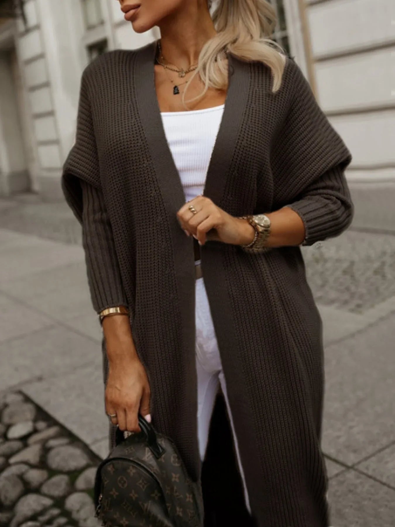 Close-up of a woman in a long brown ribbed knit cardigan, showing the texture and open front.