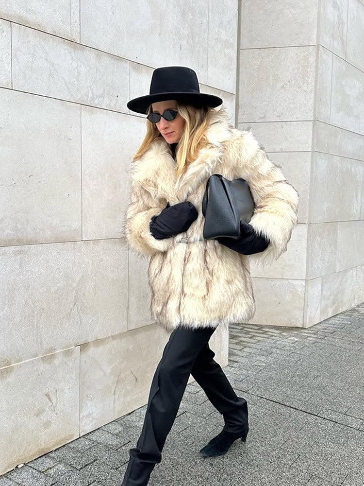Woman walking outdoors in a cream-colored faux fur coat and black accessories.