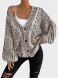 Full body shot of a woman wearing a cream oversized chunky knit cardigan, light wash jeans, and sneakers.