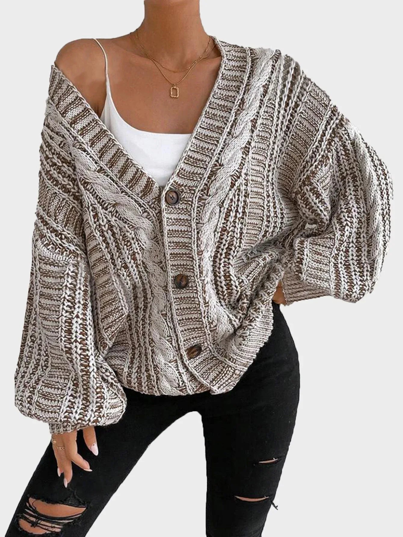 Full body shot of a woman wearing a cream oversized chunky knit cardigan, light wash jeans, and sneakers.