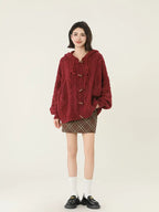 Fashionable woman posing in a red cable knit hooded cardigan