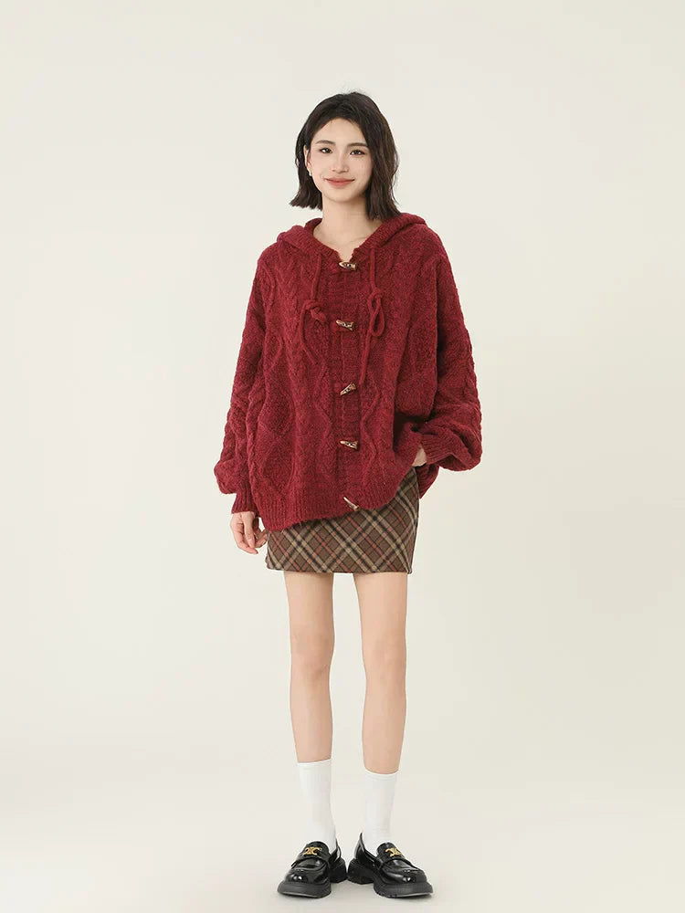 Fashionable woman posing in a red cable knit hooded cardigan