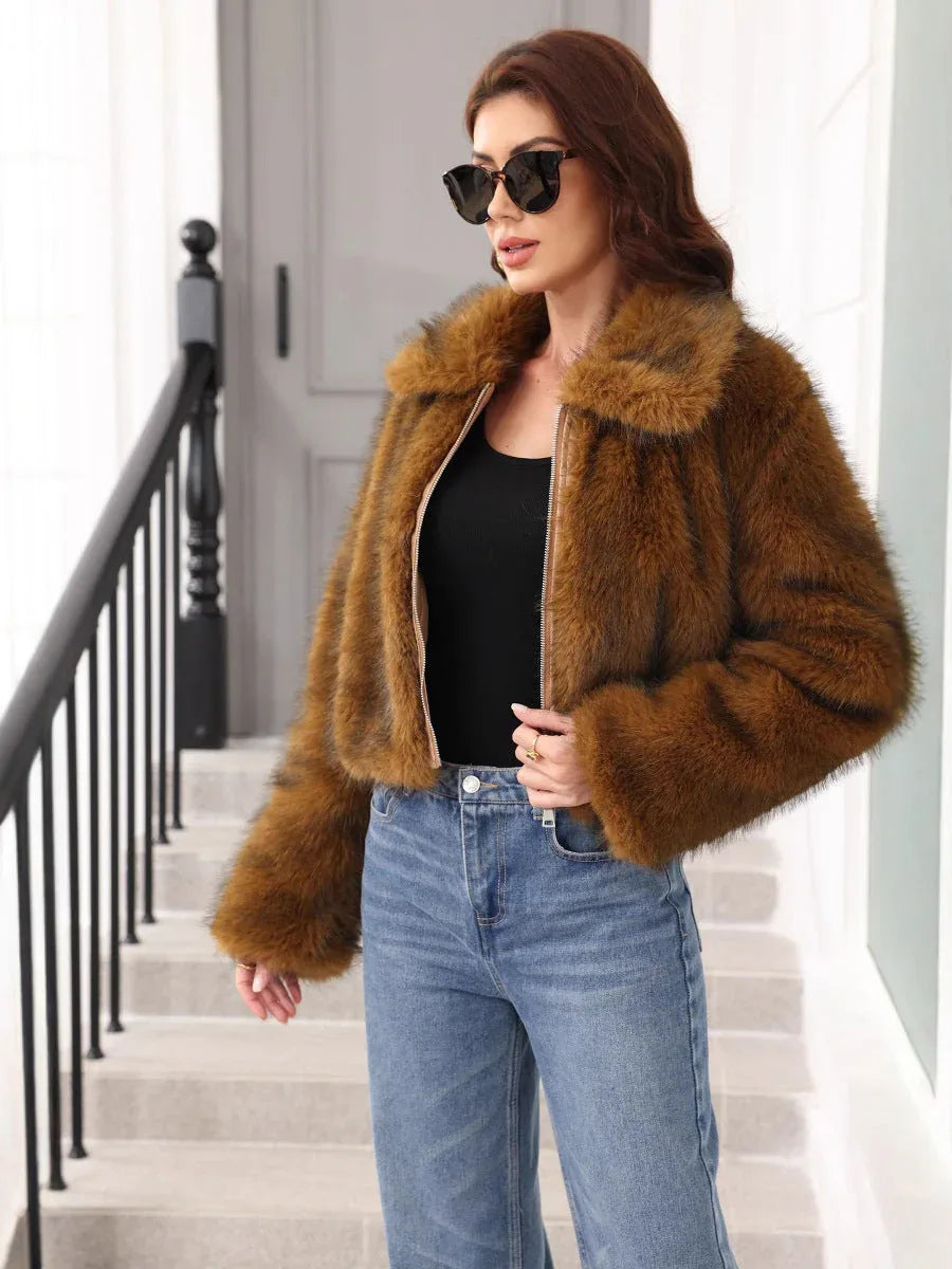 Woman wearing a brown cropped faux fur jacket with a zipper and collar, paired with blue jeans. Main image