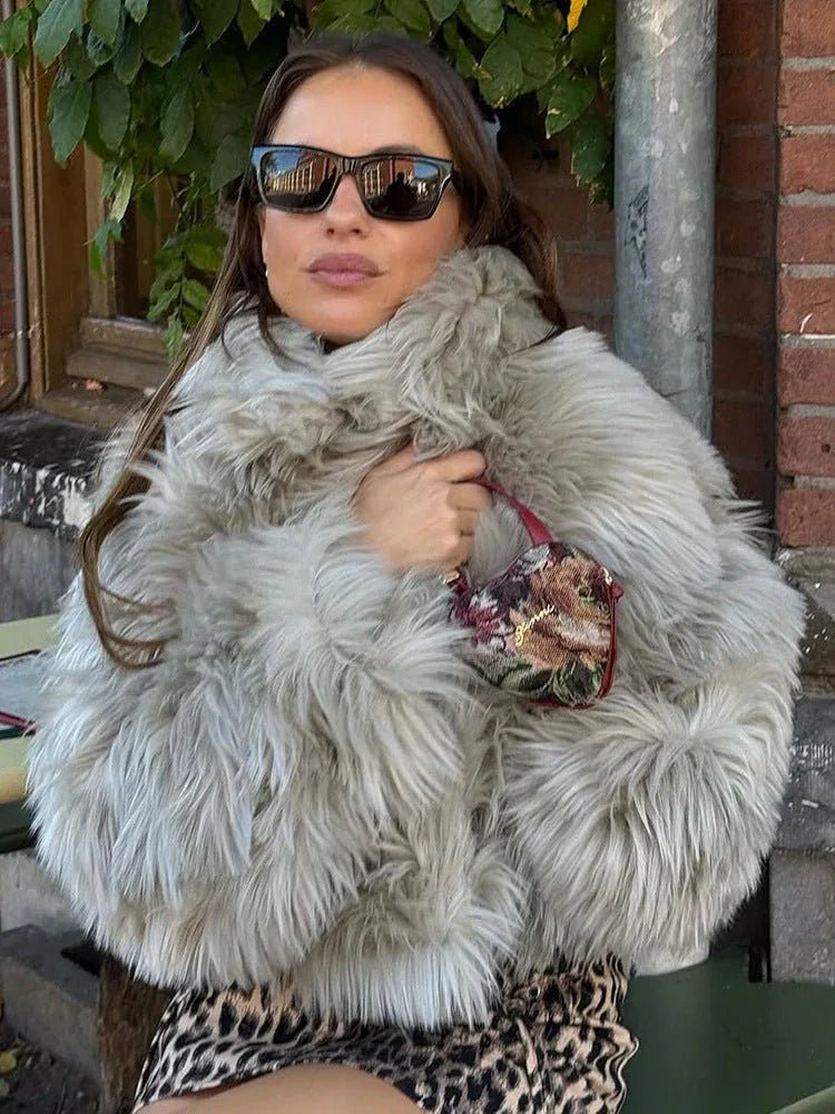 Woman wearing a light grey faux fur jacket with a leopard print skirt and sunglasses Main image