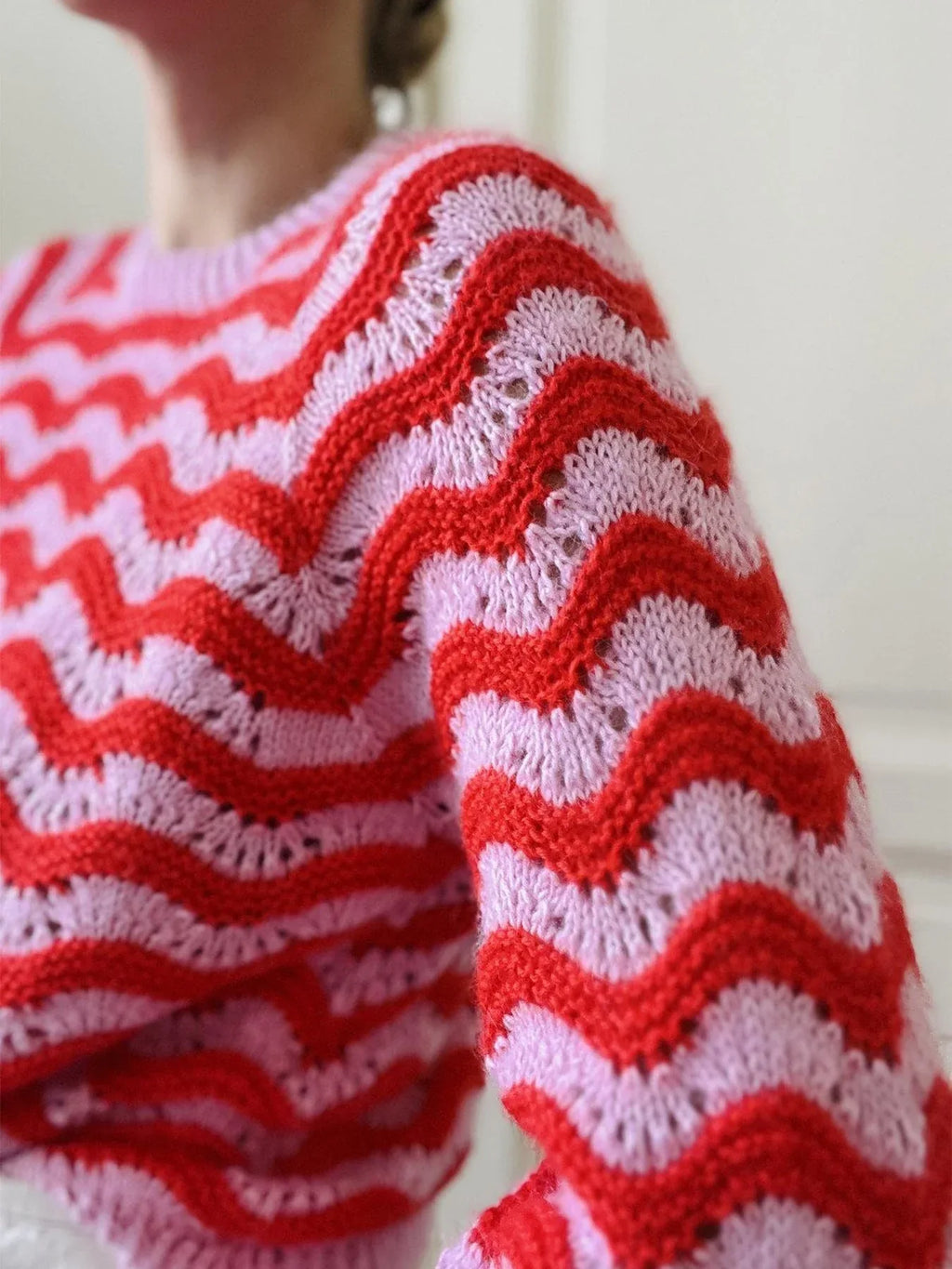 Detail of the shoulder and sleeve of a red and pink knit sweater