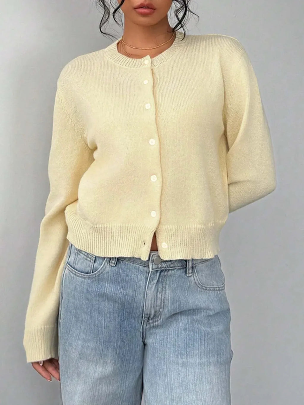Front view of a woman in a yellow cropped cardigan over a white camisole.