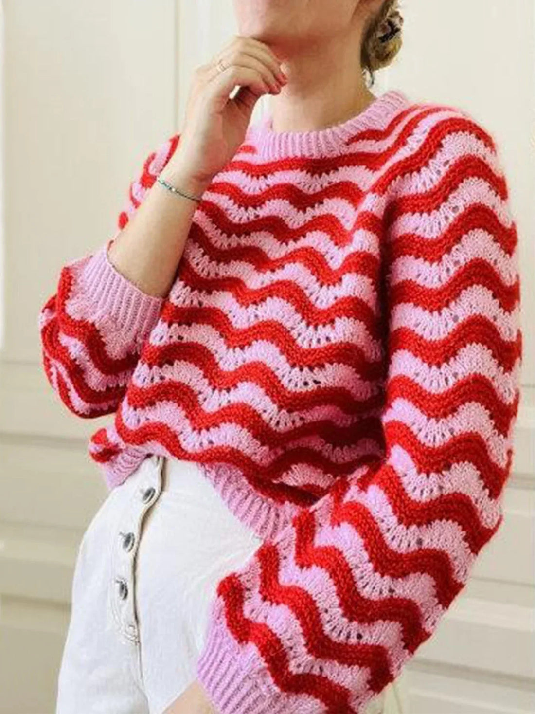 Woman wearing a red and pink striped knit sweater with long sleeves and a crew neck