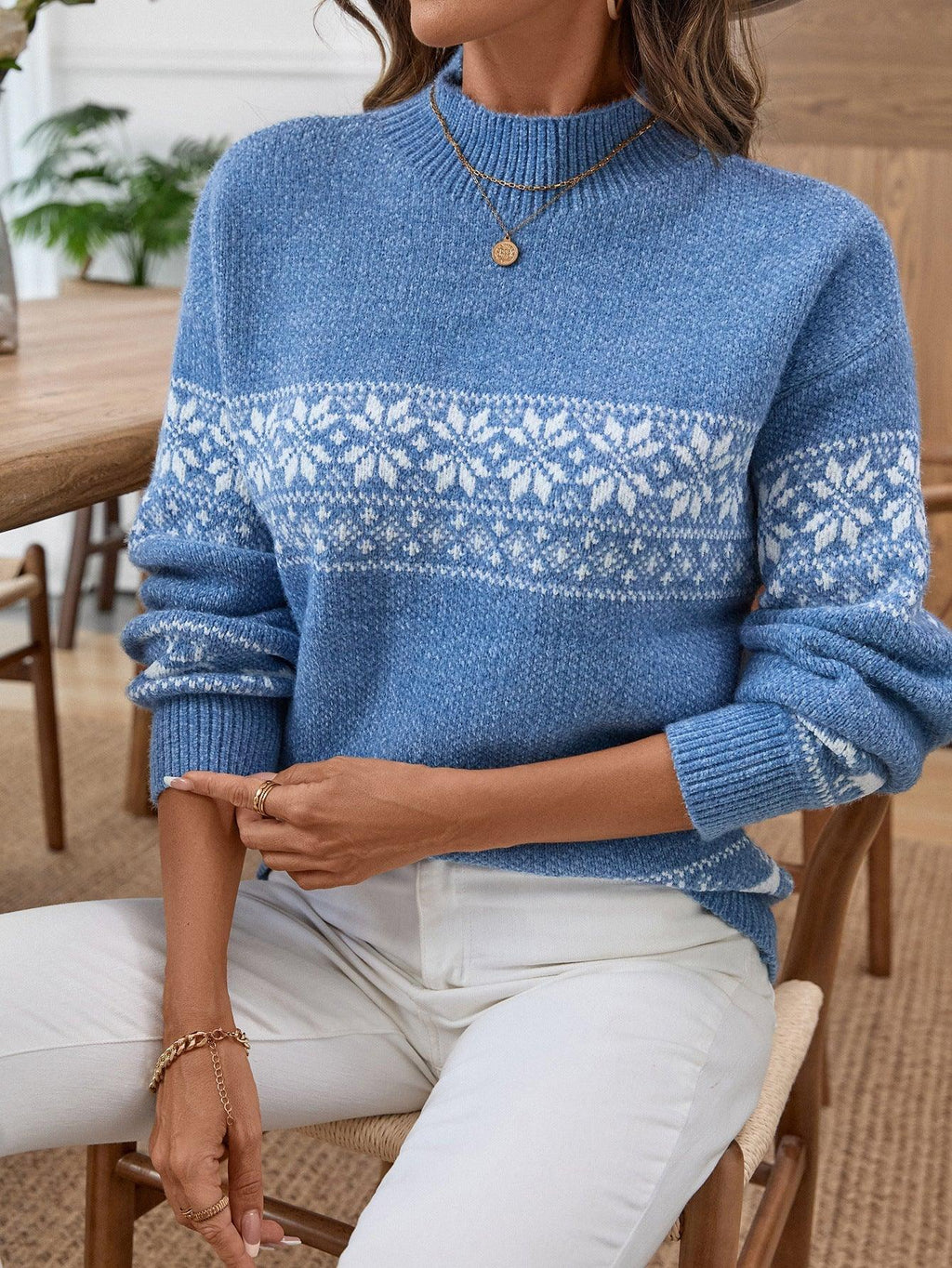 Close-up of a woman's arm in a blue Nordic snowflake mock neck sweater