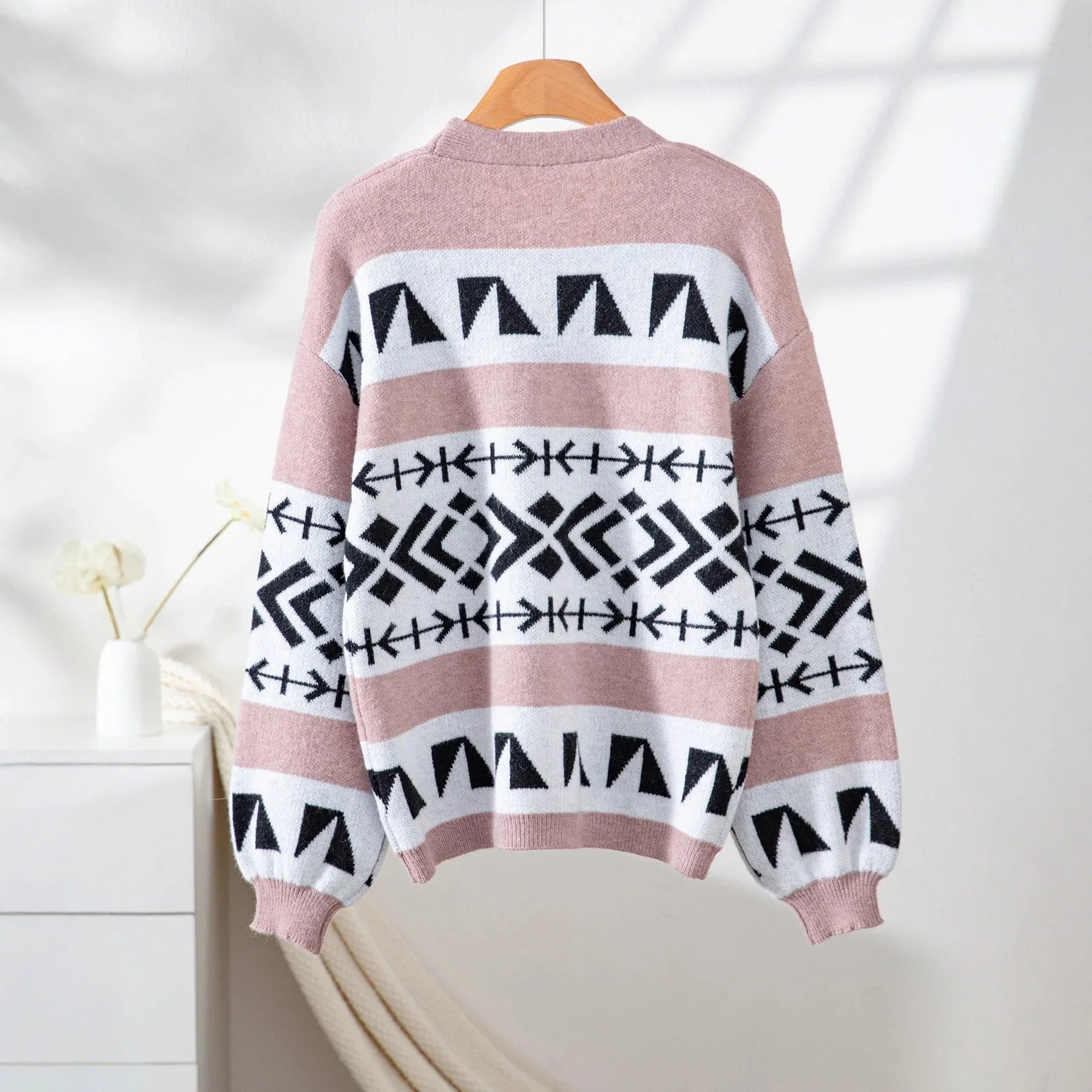 Back view of a pink, white, and black geometric pattern knit cardigan with balloon sleeves.