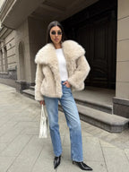 Woman styled in a white faux fur jacket with a quilted handbag