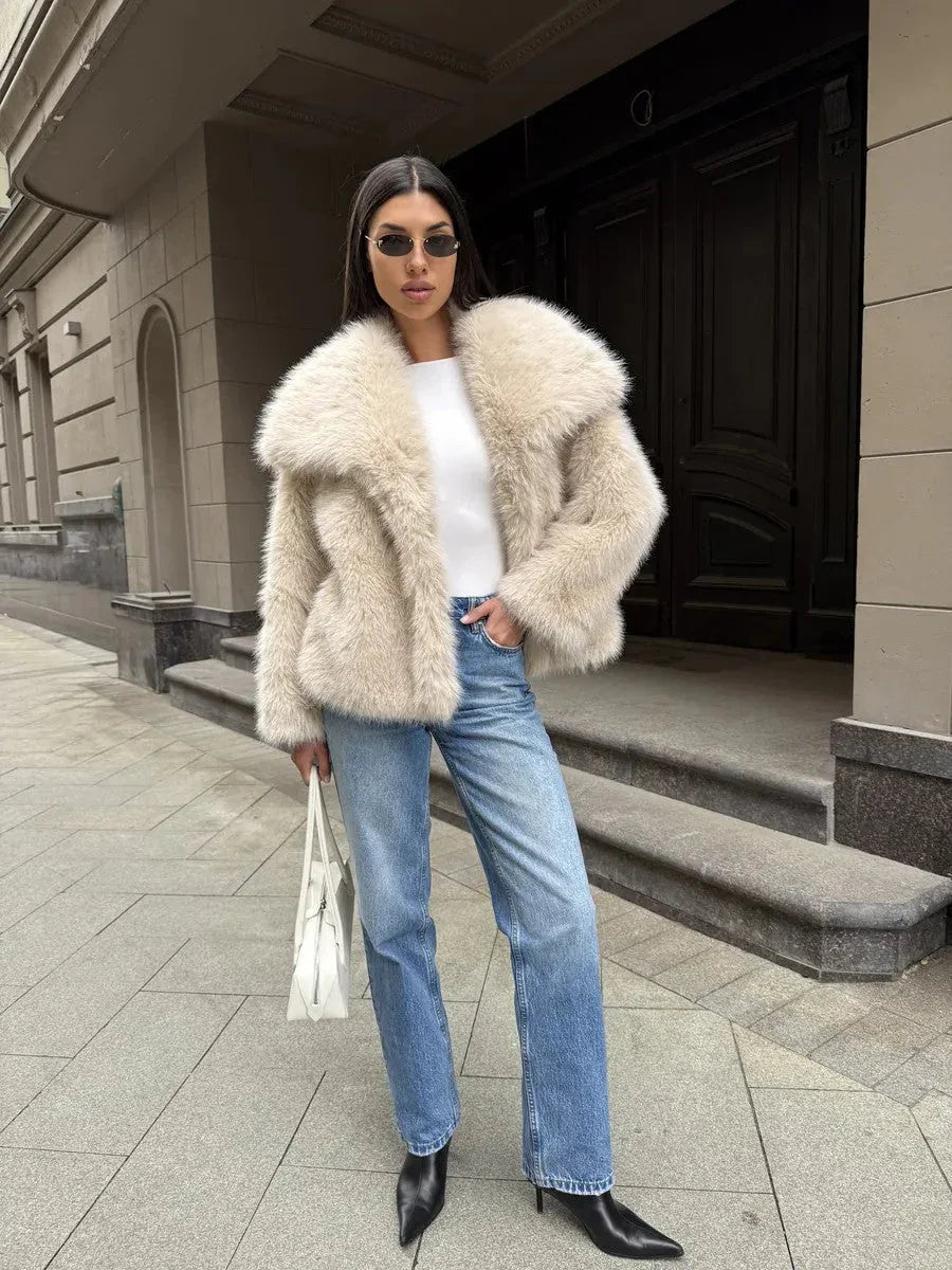 Woman styled in a white faux fur jacket with a quilted handbag