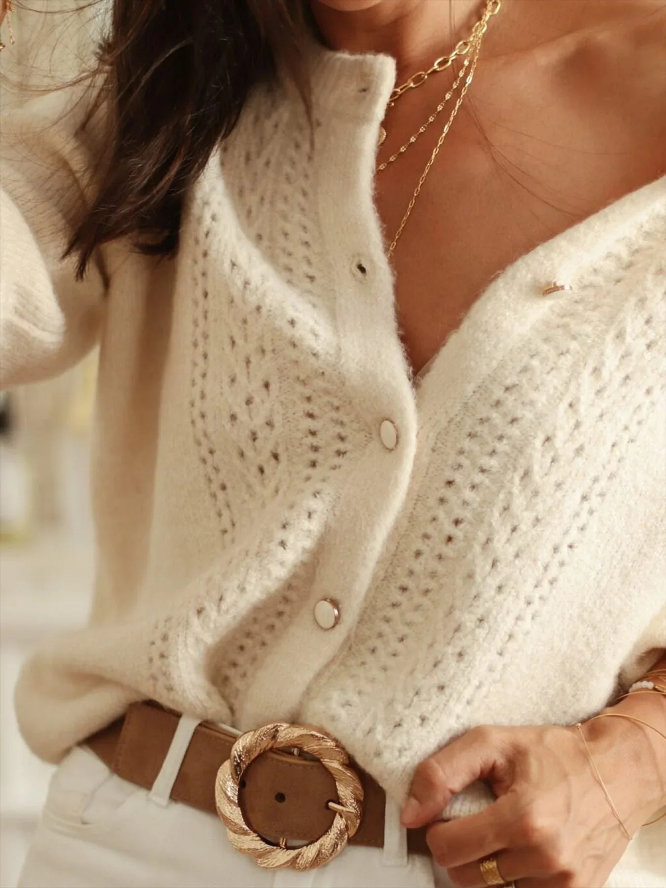 Detail of cream knit cardigan with button front and open knit pattern