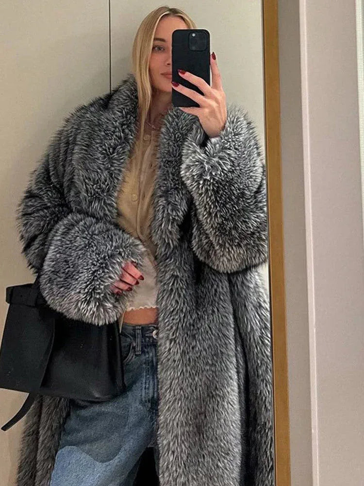 Woman taking a mirror selfie wearing a long grey faux fur coat with lapel collar and full length sleeves.