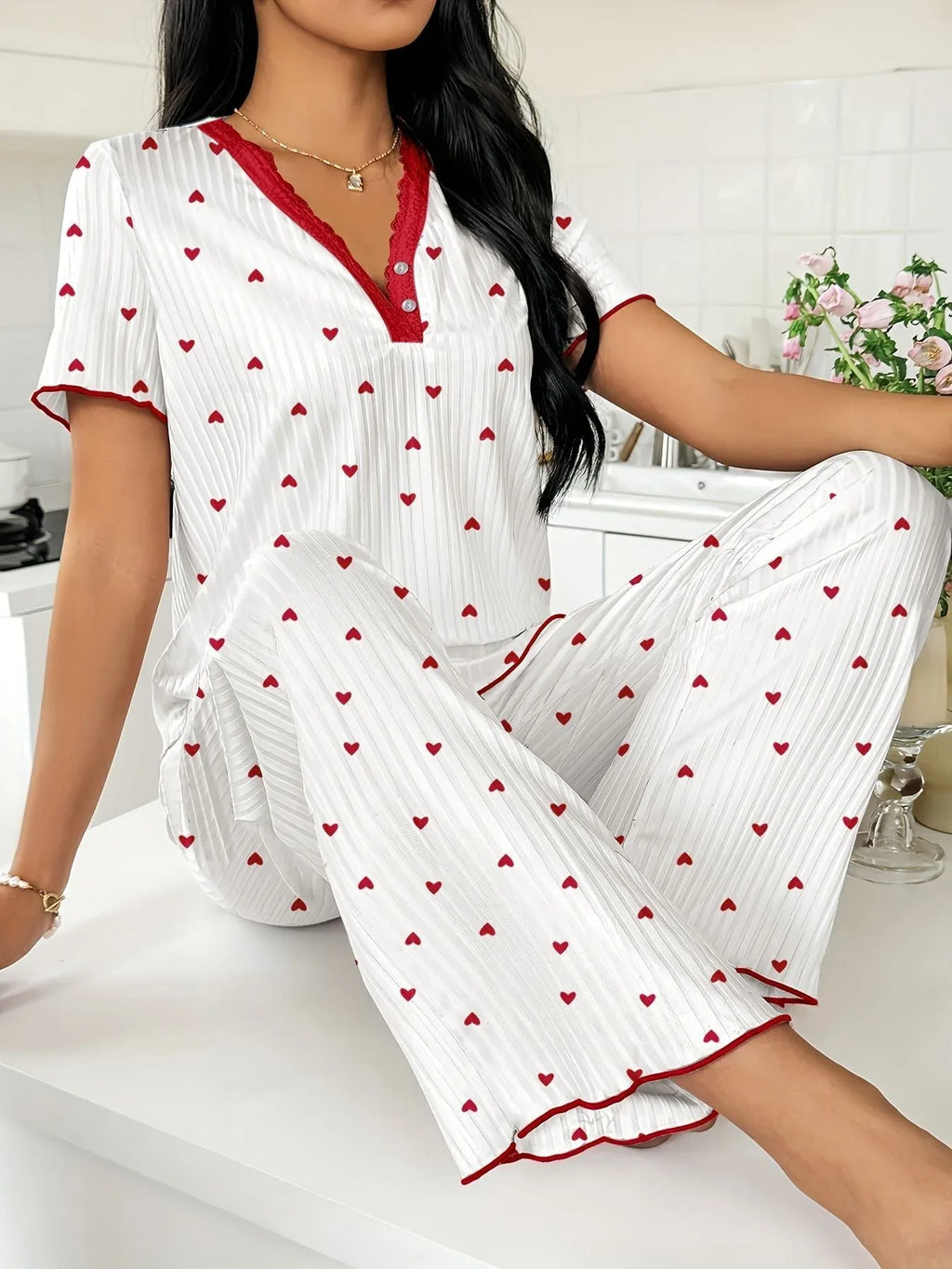 Close-up of a woman wearing a white pajama set with red hearts and red trim, showing neckline detail.