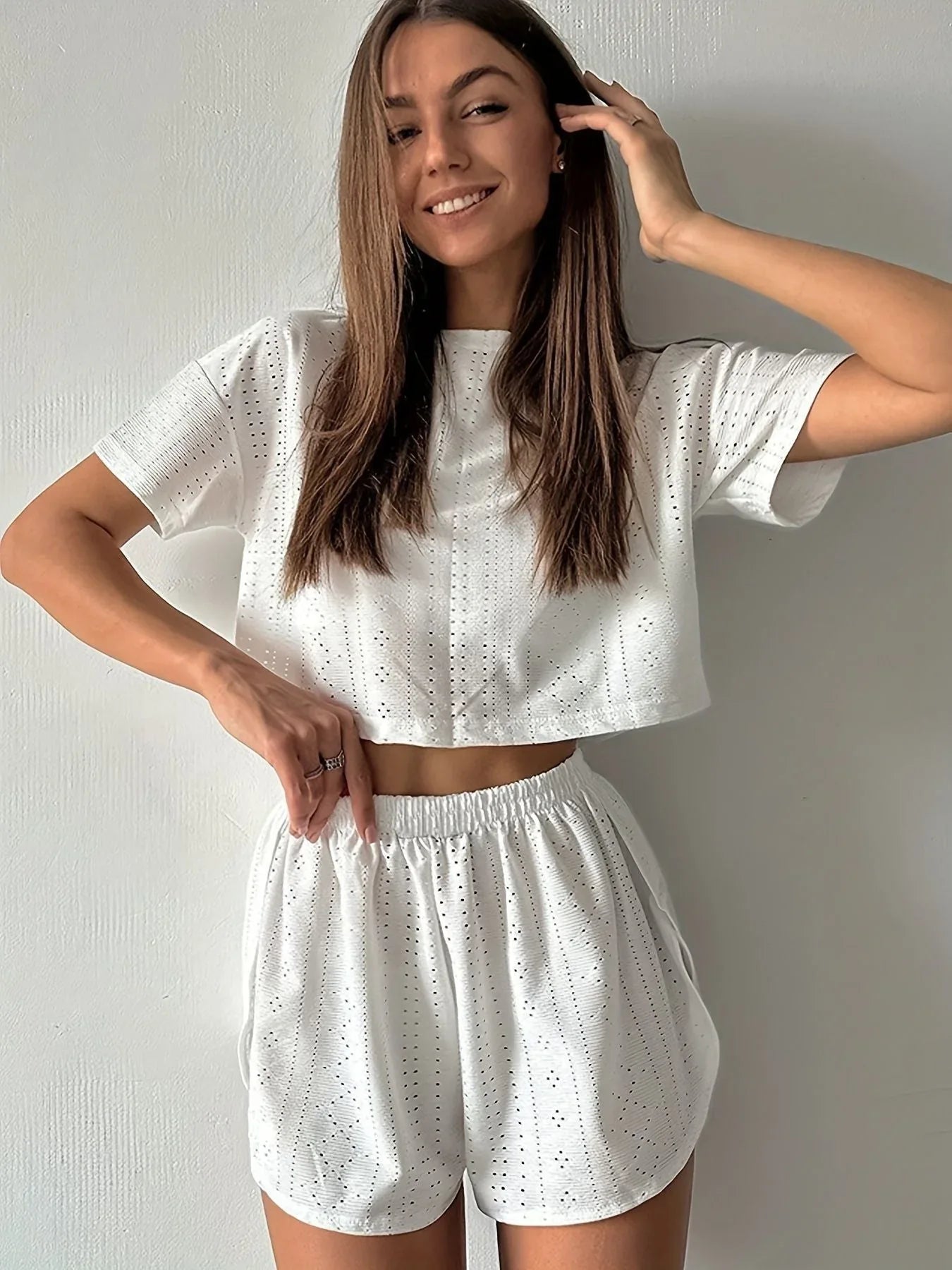 Woman wearing a white cropped eyelet t-shirt and matching white eyelet shorts