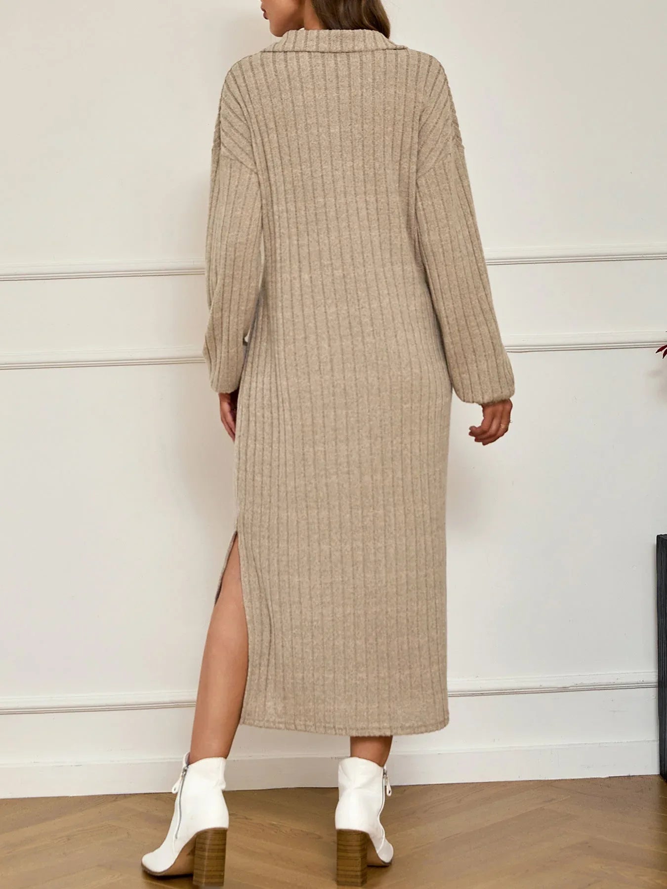 Back view of a woman in a beige ribbed knit maxi dress with a side slit