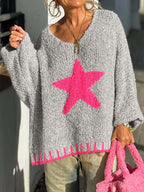 Woman holding a pink fuzzy bag while wearing a gray knit sweater with a pink star graphic.
