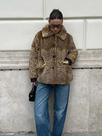 Woman in a leopard print faux fur jacket and blue jeans, looking down.