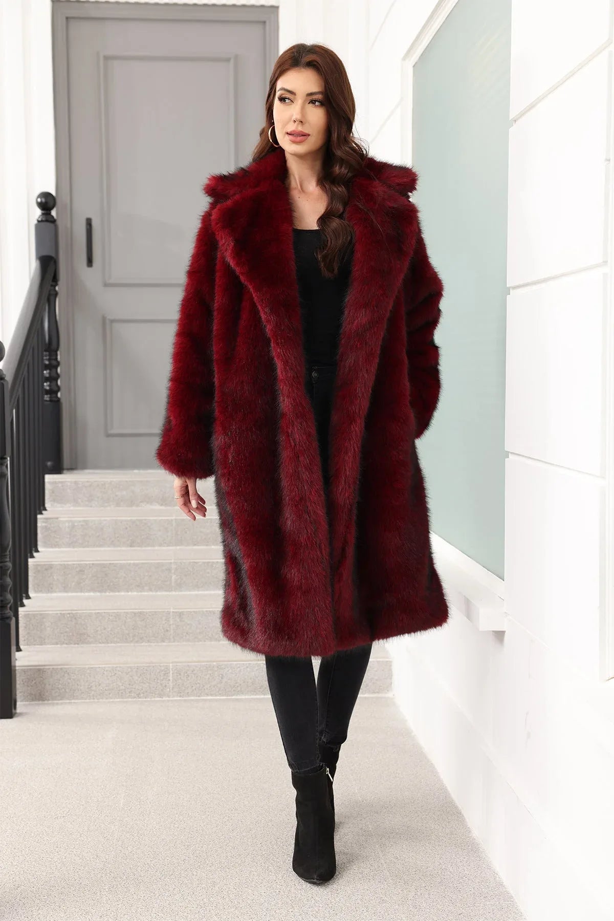 Woman wearing a long, dark red faux fur coat with a relaxed fit and notch lapel collar, standing on stairs.