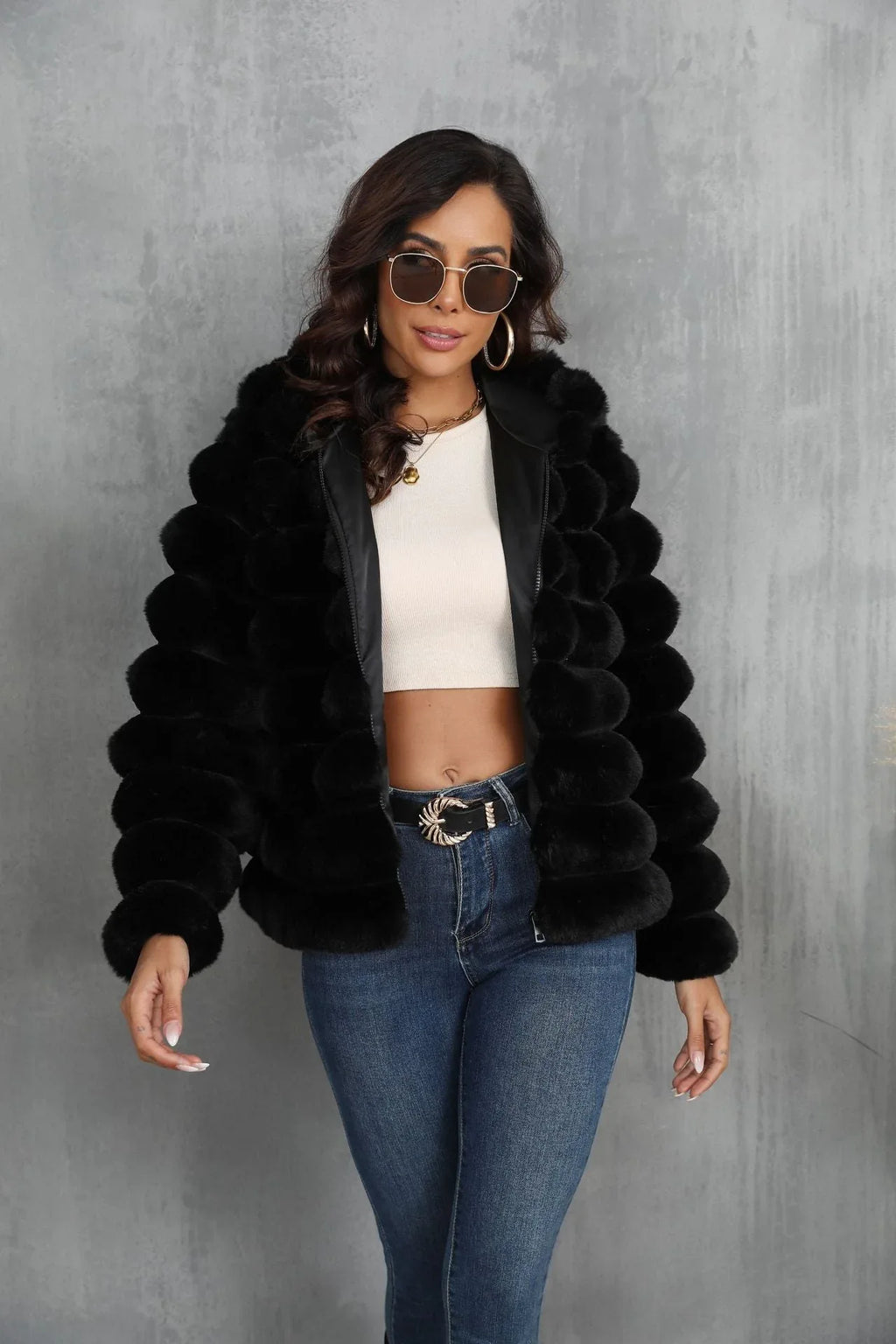 Woman in a black hooded faux fur jacket, showcasing the zipper closure and cropped style.