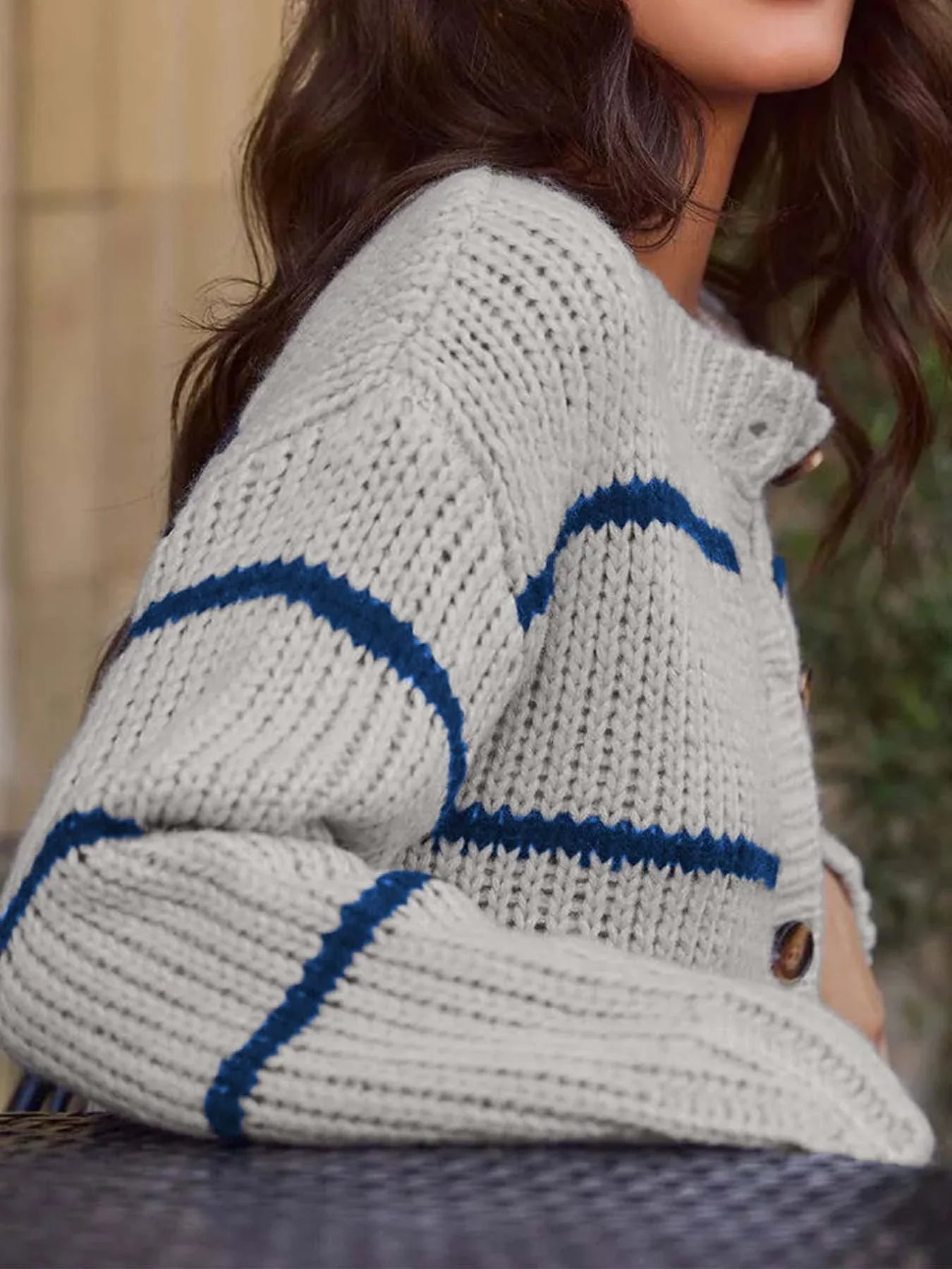 Close-up of the knit texture and striped pattern on a gray cardigan.