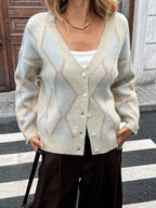 Close-up of a woman wearing a cream argyle knit cardigan with a white tank top.